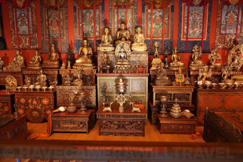 Tibetan Buddhist shrine display with gilded statues, thangka paintings, and ornate altar cabinets, ISO 3200 sample