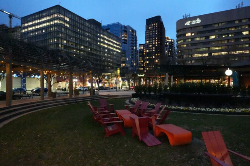 City courtyard scene with red chairs and lit skyline at dusk, ISO 20000 noise test
