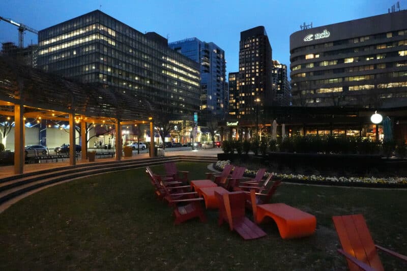 Twilight plaza with red chairs and illuminated buildings showing visible grain at ISO 25600