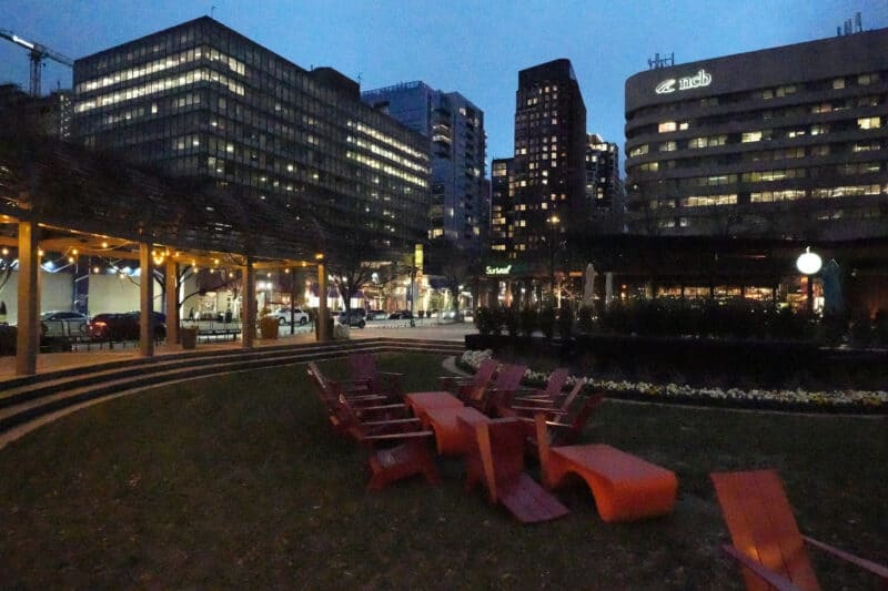 Nighttime courtyard with red chairs and city lights showing heavy noise at ISO 80000