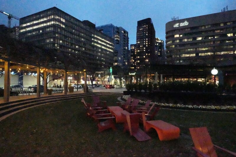 Very high ISO 102400 test shot of dark city courtyard with red chairs and lit towers