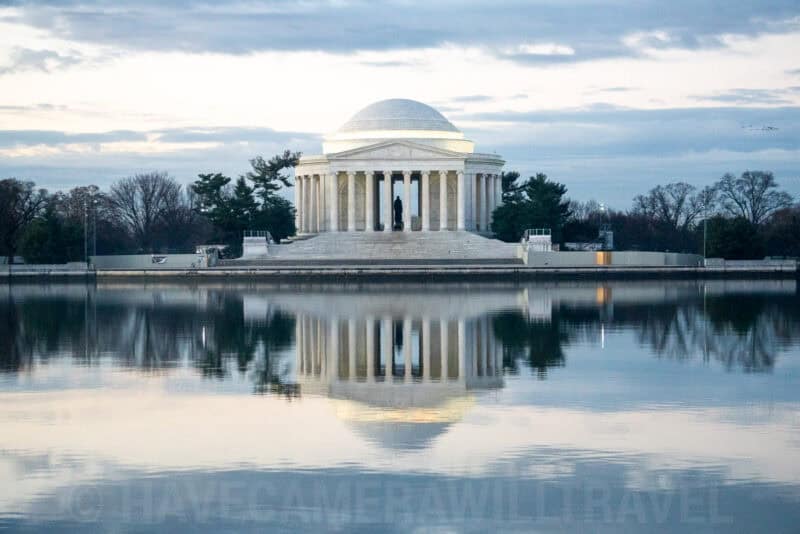 The Jefferson Memorial's domed rotunda and columns reflected in the Tidal Basin at dusk