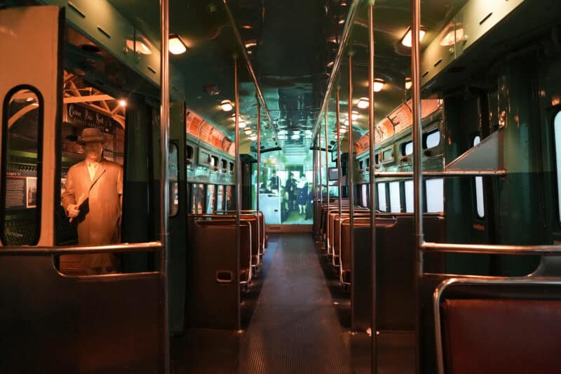 Interior of a restored vintage streetcar with a mannequin passenger and rows of empty seats