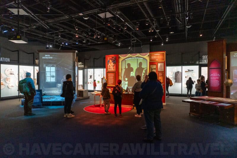 Museum visitors viewing an illuminated exhibit display in a history gallery