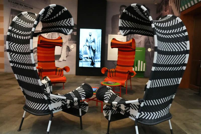 Sculptural woven chairs in bold zigzag patterns arranged around a museum exhibit space