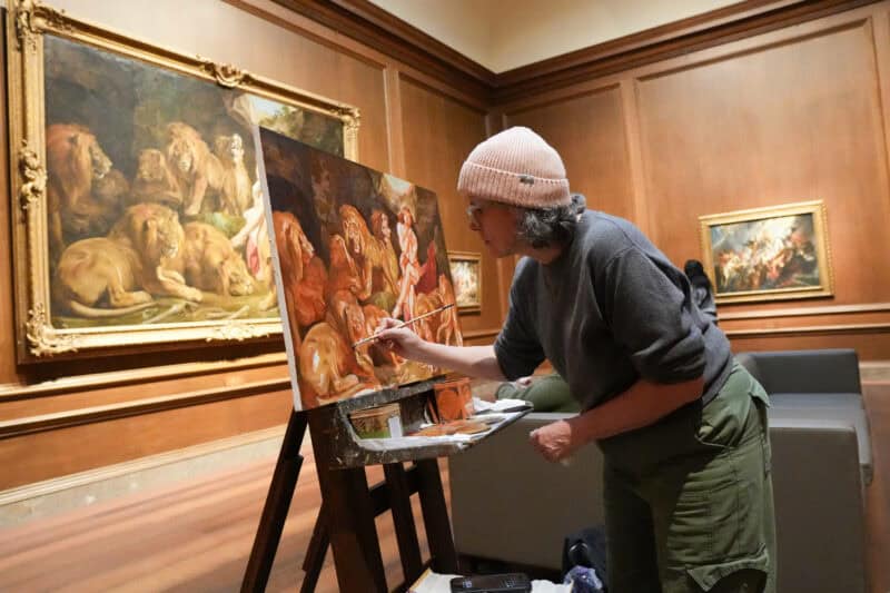 Artist copying a lion painting on an easel inside a wood-paneled museum gallery