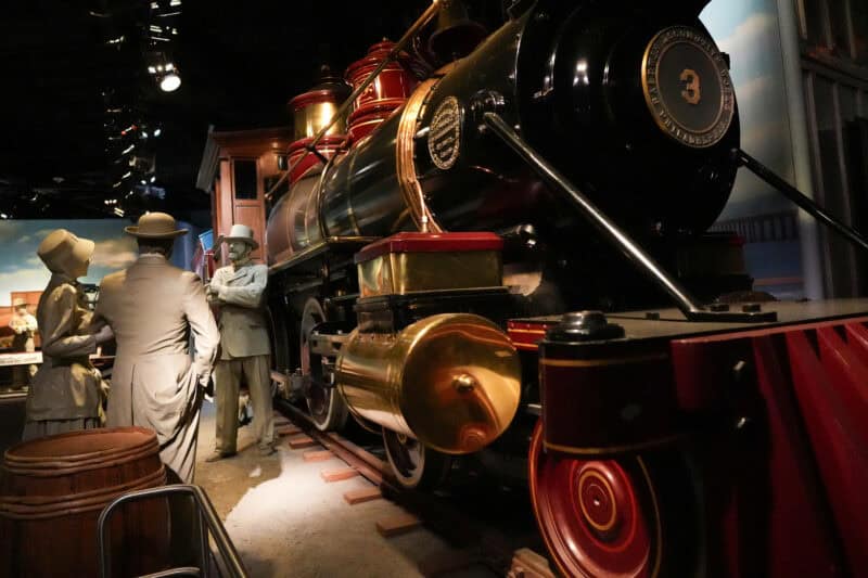 Vintage steam locomotive replica with mannequins in period clothing at a museum train exhibit