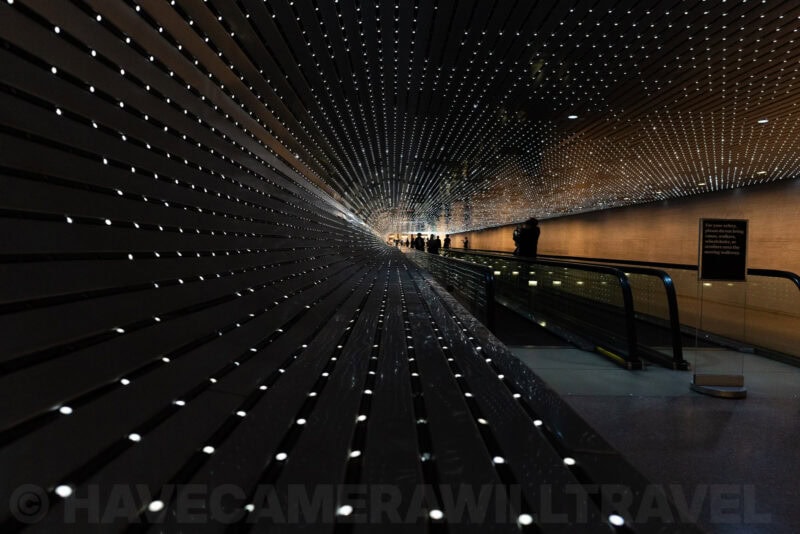 Illuminated tunnel walkway lined with sparkling lights and silhouetted visitors
