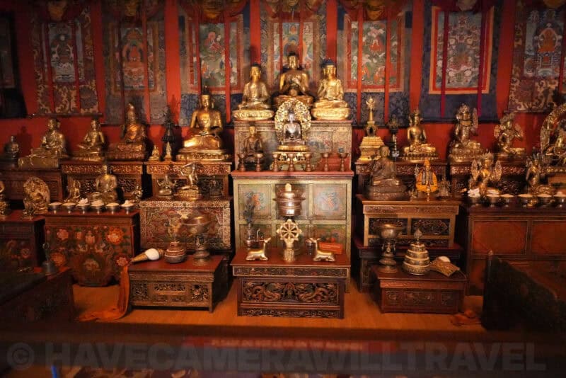 Tibetan Buddhist shrine room with gilded Buddha statues and ornate painted cabinets