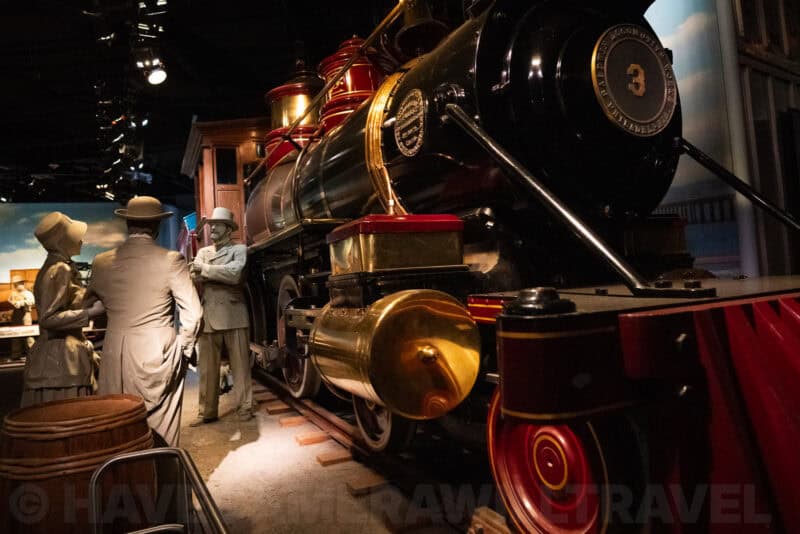 Vintage steam locomotive replica with mannequins in period dress at a museum exhibit