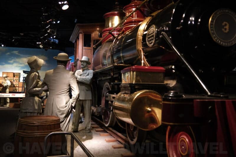 Life-size figures beside a vintage steam locomotive in a museum diorama at ISO 64, sharp and clean