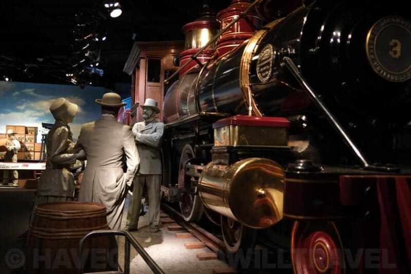 Life-size figures beside a vintage steam locomotive in a museum diorama at ISO 80 with crisp detail