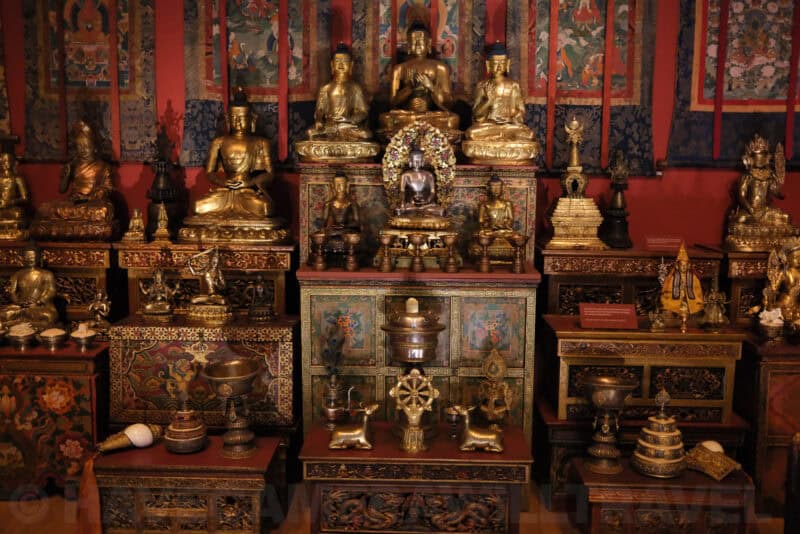 Gilded Buddhist statues and shrine display in a museum exhibit at ISO 10000 with heavy noise