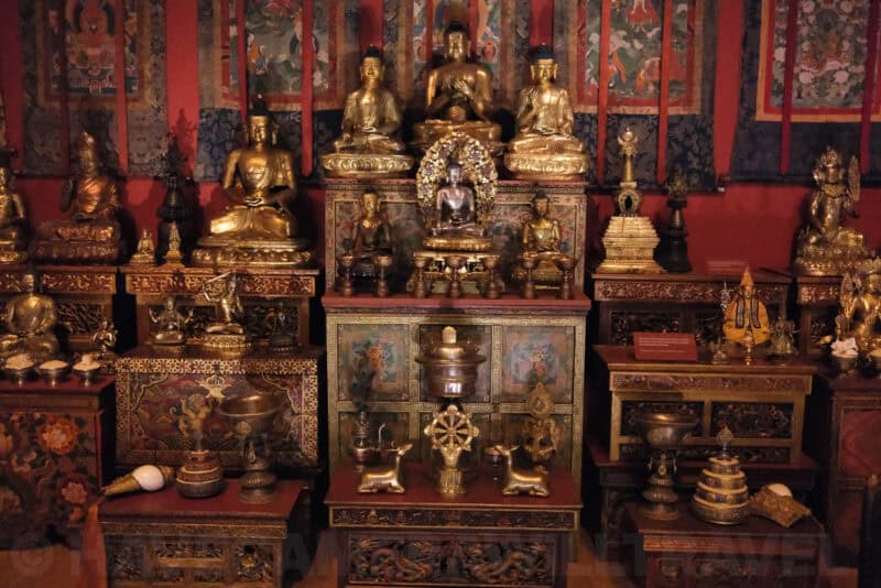 Gilded Buddhist statues and shrine display in a museum exhibit at extended ISO 25600 with heavy noise