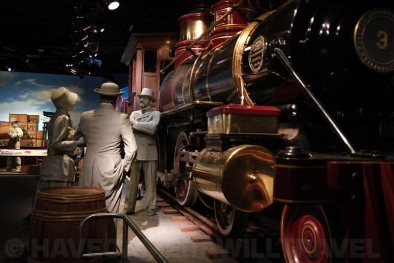 Life-size figures beside a vintage steam locomotive in a museum diorama at ISO 1250 with moderate noise
