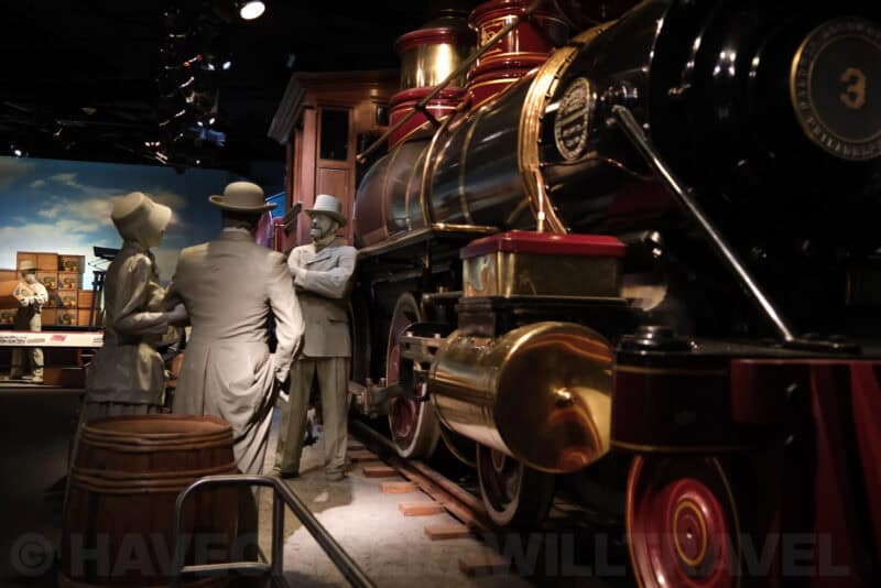 Life-size figures beside a vintage steam locomotive in a museum diorama at ISO 2000 with softened detail