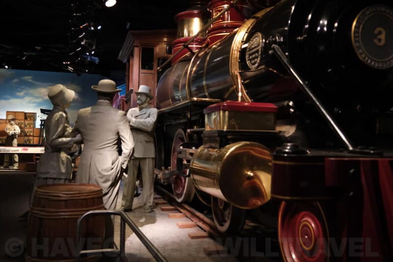 Life-size figures beside a vintage steam locomotive in a museum diorama at ISO 2500 with visible high-ISO noise