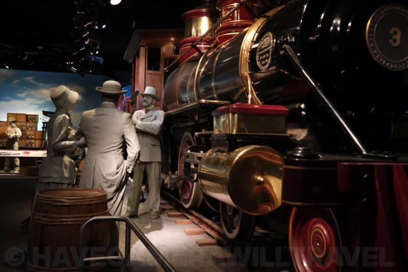 Life-size figures beside a vintage steam locomotive in a museum diorama at ISO 5000 with heavier noise