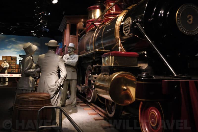 Life-size figures beside a vintage steam locomotive in a museum diorama at ISO 8000 with strong visible grain