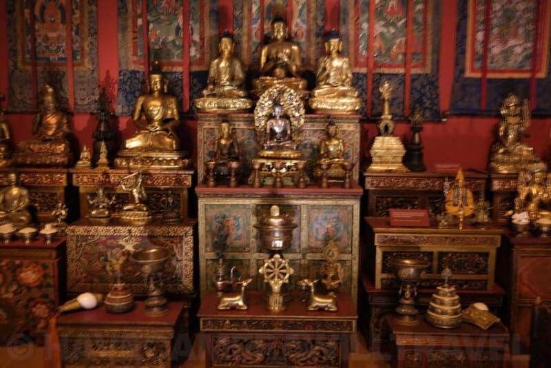 Gilded Buddhist statues and shrine display in a museum exhibit at ISO 64, showing minimal noise