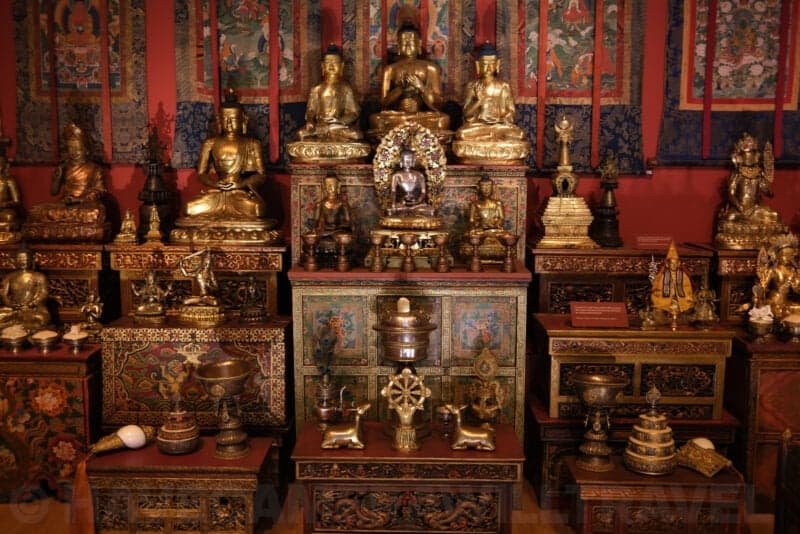 Gilded Buddhist statues and shrine display in a museum exhibit at ISO 80, still clean and detailed
