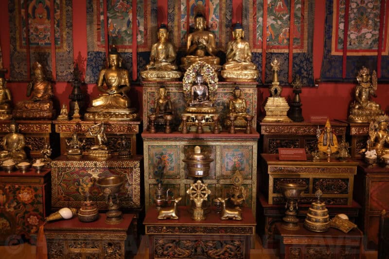 Gilded Buddhist statues and shrine display in a museum exhibit at ISO 100 with crisp detail