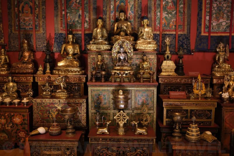 Gilded Buddhist statues and shrine display in a museum exhibit at ISO 640 with slightly more grain