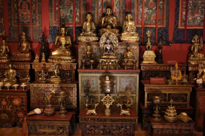 Gilded Buddhist statues and shrine display in a museum exhibit at ISO 1600 with noticeable grain