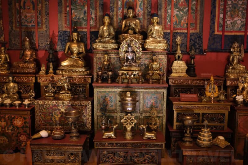 Gilded Buddhist statues and shrine display in a museum exhibit at ISO 3200 with grain in shadow areas