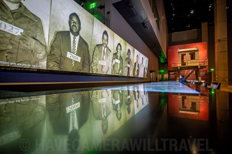 Museum exhibit with large portrait photographs reflected on a dark polished floor