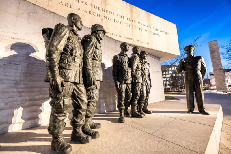 Bronze soldier statues at the Eisenhower Memorial beneath an inscribed stone wall