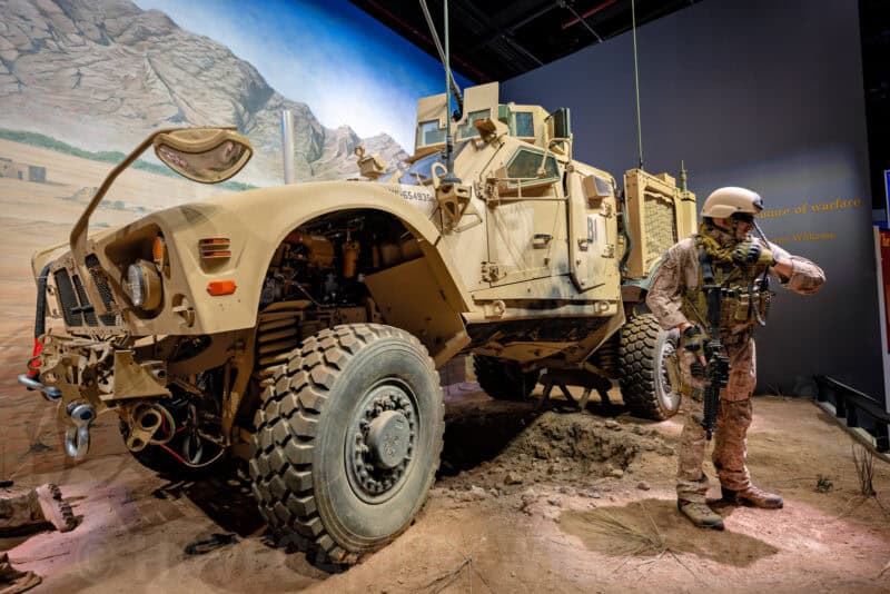 Armored military vehicle and soldier mannequin in a desert-themed museum exhibit