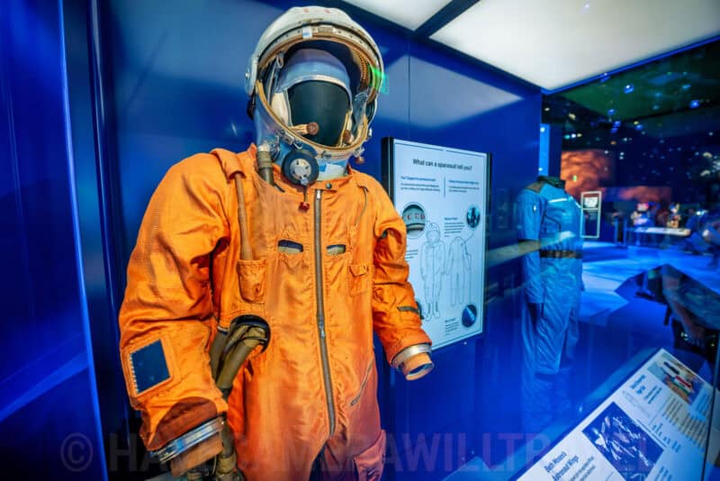 Orange Soviet-era spacesuit and helmet displayed in a museum exhibit case