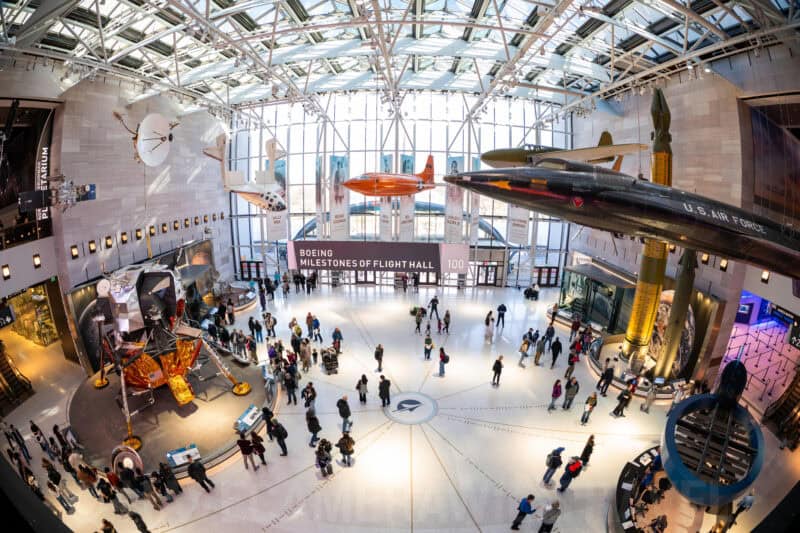 Wide fisheye view of the Boeing Milestones of Flight Hall at the National Air and Space Museum with visitors below hanging aircraft