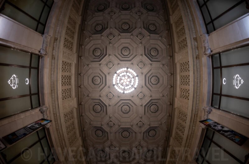 Fisheye view straight up at an ornate coffered dome ceiling with a central light fixture