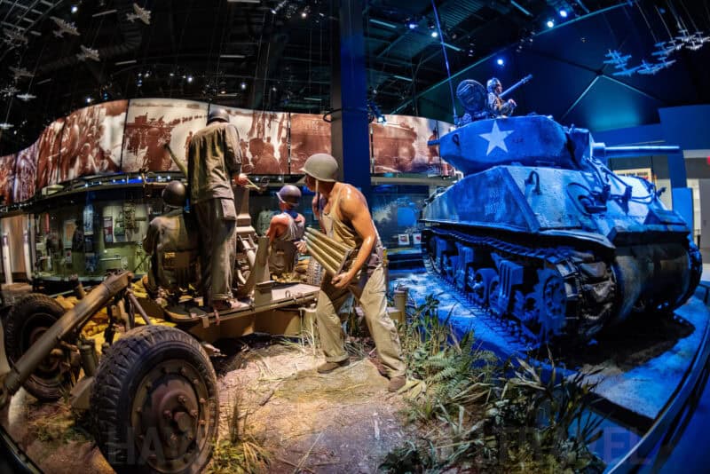 Fisheye view of a WWII battle diorama with soldier figures and a Sherman tank at a military museum