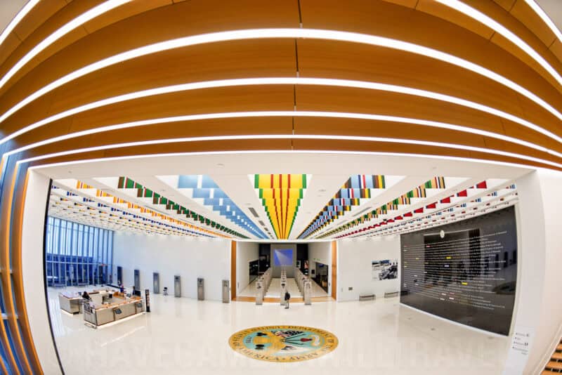 Fisheye view of a museum lobby with a ribbed wooden ceiling and colorful hanging banner display