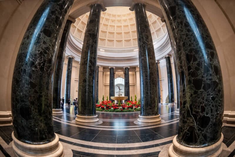 Fisheye view through dark marble columns toward a fountain in the National Gallery of Art's rotunda