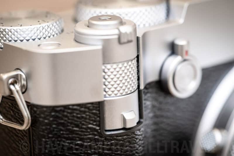Close-up of the Fujifilm GFX100RF's front teleconverter lever beneath the shutter button on its silver top plate