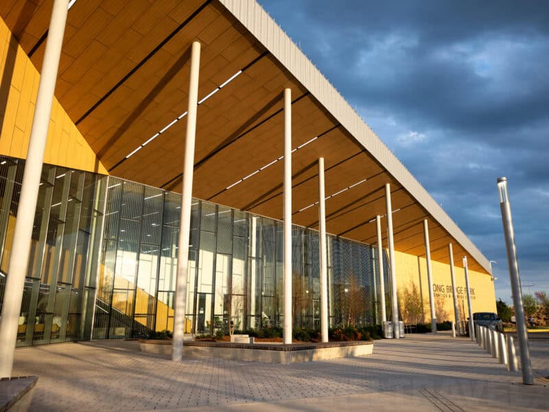 Angular wood and glass facade of Long Bridge Park building glowing at sunset
