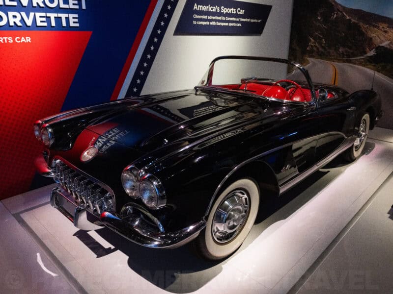 Classic black Chevrolet Corvette convertible with red interior displayed in a car museum exhibit