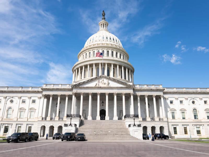 United States Capitol dome and facade with black SUVs parked at the entrance stairs