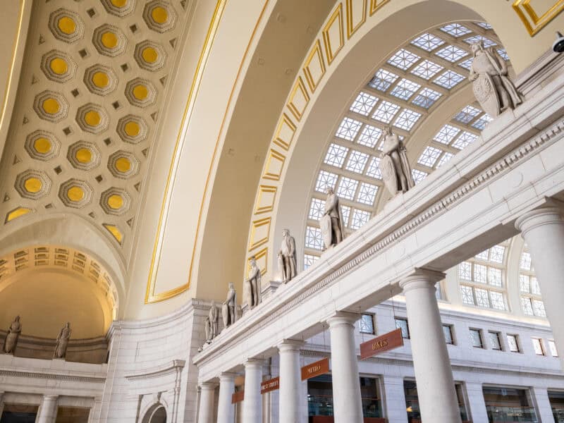 Ornate coffered ceiling and marble columns beneath statues inside Union Station's Main Hall